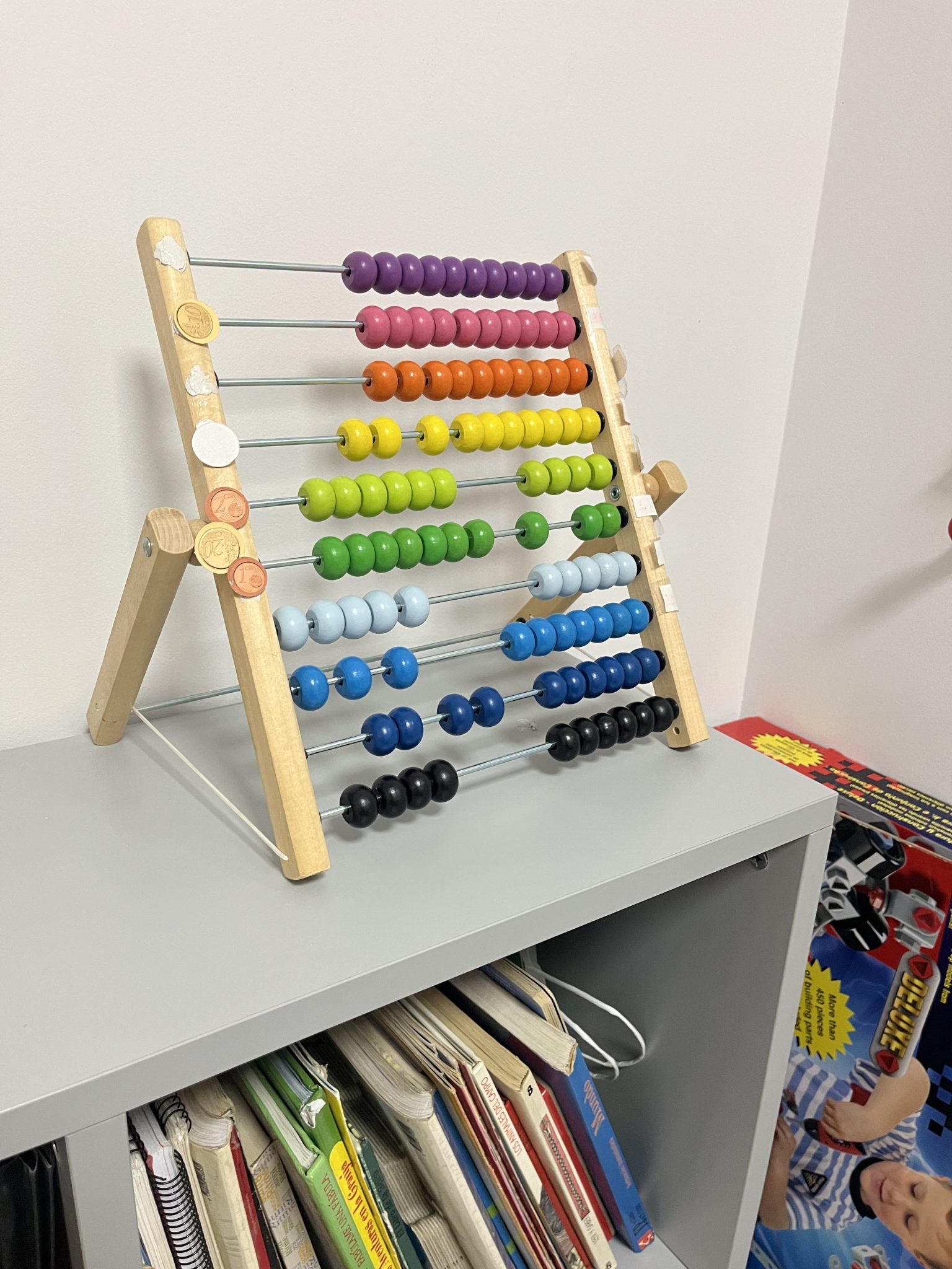 Ábaco de colores sobre estantería gris.