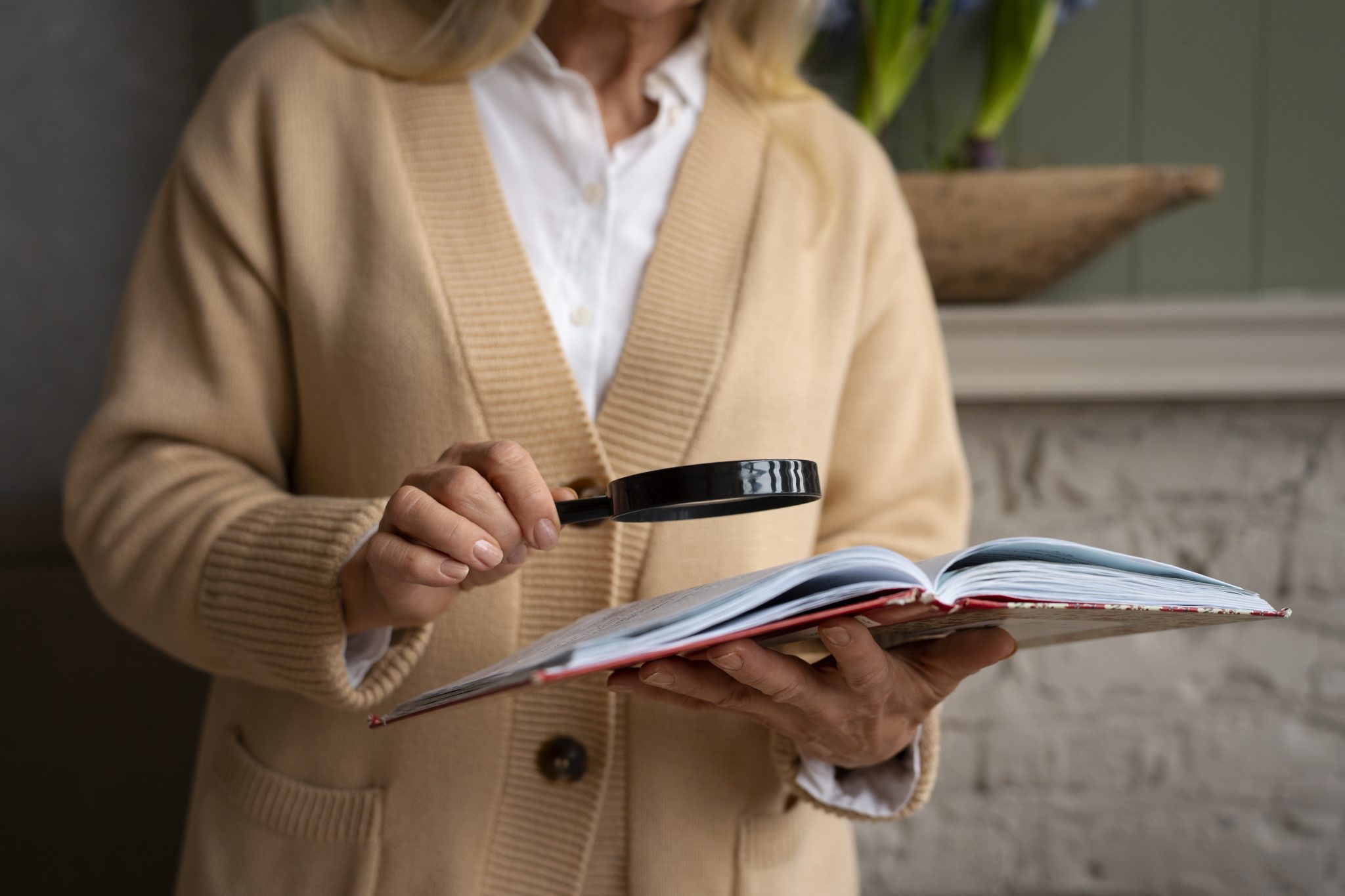 Mujer mirando un libro con una lupa.